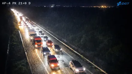 Vehículos parados en la AP-4, es de noche y tienen los faros encendidos.