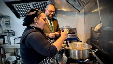 Germán Boardo y la cocinera mirando la olla.