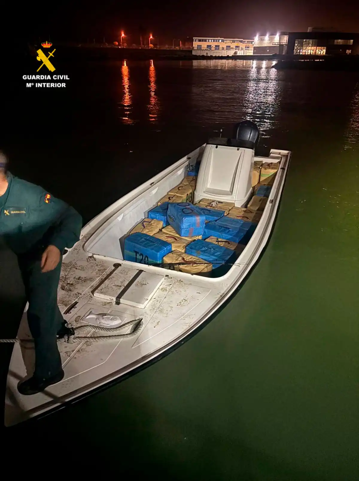 Una lancha blanca atracada en el muelle con un agente en su interior y con fardos de hachís visibles en cubierta