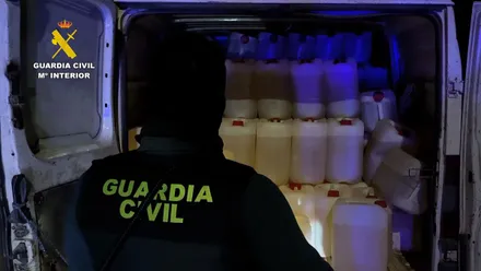 Agente de la Guardia Civil ante una furgoneta cargada con bidones de gasolina.