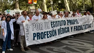 Médicos manifestándose portando una pancarta blanca con letras azules.