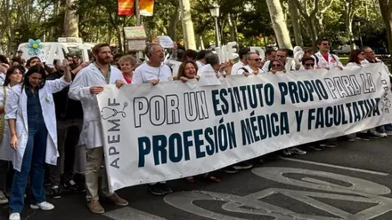 Médicos manifestándose portando una pancarta blanca con letras azules.