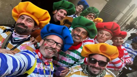 Grupo de personas con indumentaria de colores vistosos de Carnaval posan para una fotografía.