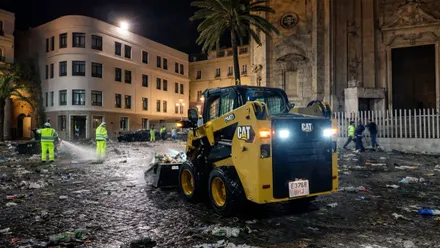 Maquina retirando residuos de las calles, operarios con monos amarillo fluorescente.