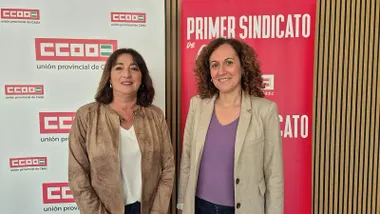 La secretaria provincial de CCOO Cádiz, Inmaculada Ortega, situada a la izquierda, aparece junto a la secretaria general de CCOO Andalucía, Nuria López, durante un acto sindical. Ambas posan sonrientes frente a un fondo con logotipos de CCOO.