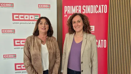La secretaria provincial de CCOO Cádiz, Inmaculada Ortega, situada a la izquierda, aparece junto a la secretaria general de CCOO Andalucía, Nuria López, durante un acto sindical. Ambas posan sonrientes frente a un fondo con logotipos de CCOO.