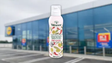 Envase de aceite virgen en spray con un supermercado Lidl borroso tras el mismo.