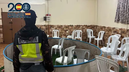 Recinto para peleas de gallos, hay un agente de la Policía Nacional de espalda y con pasamontañas.