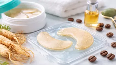 Dos parches para aplicar con un tono anaranjado, cerca hay un tarro de líquido y ginseng.