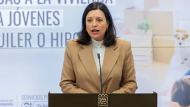 Patricia Cavada, con chaqueta crema, hablado desde el atril.