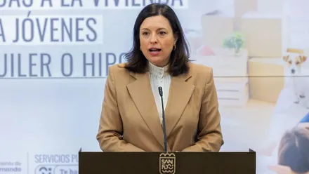 Patricia Cavada, con chaqueta crema, hablado desde el atril.