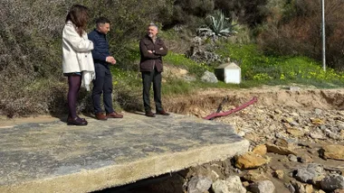 Tres personas a pie de playa sin apenas arena y muchas rocas.