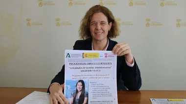 La delegada Manuela Pérez sentada en una mesa de madera y sosteniendo la propuesta de los cursos en sus manos.