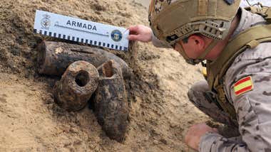 Tres proyectiles y un soldado verificando su estado.