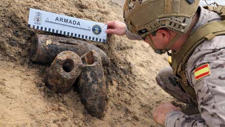 Tres proyectiles y un soldado verificando su estado.