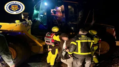 Personal de salvamento junto a una excavadora y uno de los rescatados.