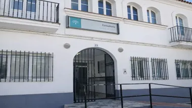 Puerta de acceso al Centro de Salud en Alcalá de los Gazules. Edificio en blanco y la zona baja en gris.