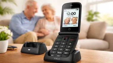 Teléfono en primer término y dos personas mayores al fondo.