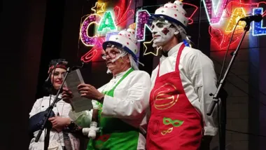 Tres personas disfrazadas y maquilladas en el escenario en el momento del pregón del Jartible a cargo de José Antonio González Boy.