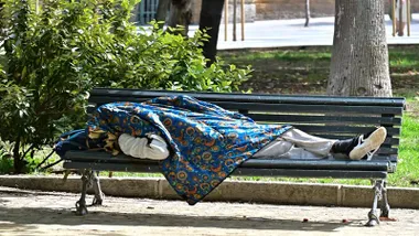 Una persona sin hogar descansa en un banco de Cádiz