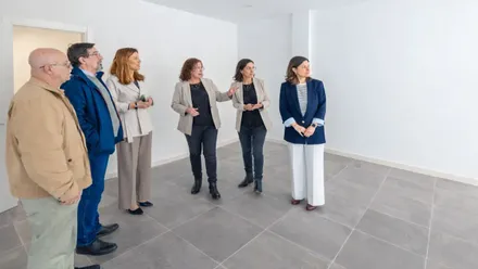 Momento de la visita de la alcaldesa, está junto a cinco personas más, miran una habitación blanca.