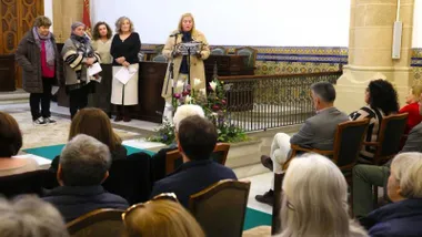 Momento del discurso del 8M en Rota, mucho público sentado, habla una mujer.