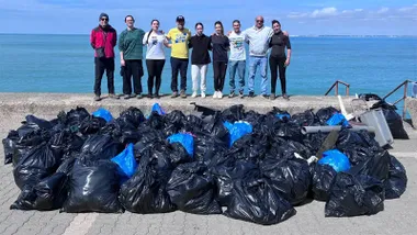 Quique Bolsistas y el grupo de voluntarios y voluntarias con la basura recogida.