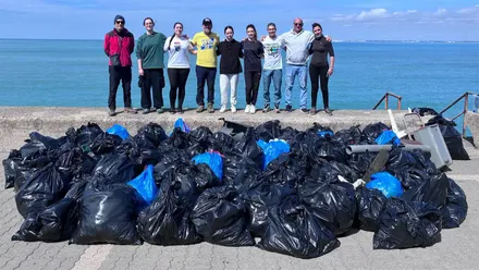 Quique Bolsistas y el grupo de voluntarios y voluntarias con la basura recogida.