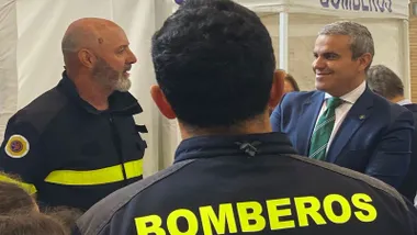 Bomberos hablando con el representante que va de chaqueta y corbata.