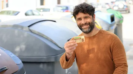 El delegado Roberto Palmero junto a unos contenedores y sosteniendo una tarjeta en la mano.