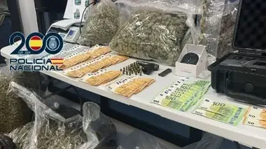 Una mesa con dinero, billetes de 50 y 100 euros, hachís y armas.