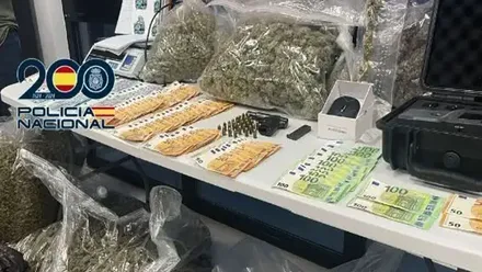 Una mesa con dinero, billetes de 50 y 100 euros, hachís y armas.