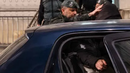 Detenido, esposado, es metido en un coche azul por un Guardia Civil.