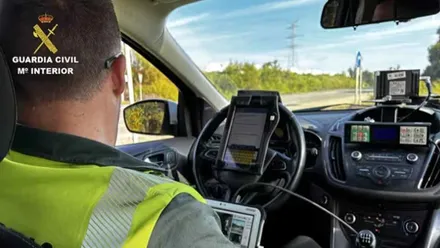 Agente de la Guardia Civil en su automóvil controlando la velocidad en una carretera.