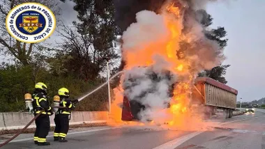 llamas muy altas y bomberos apagando el incendio de un camión.