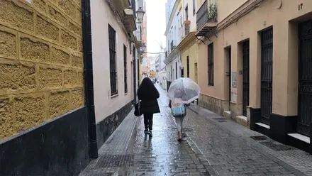 Una madre y su hija van al colegio bajo los paraguas en una mañana lluviosa en Cádiz
