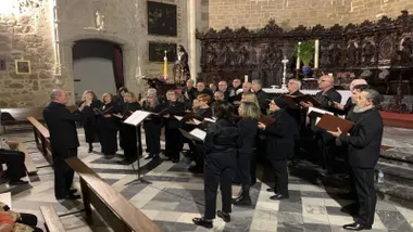 Miembros del Orfeón de negro cantando en coral.