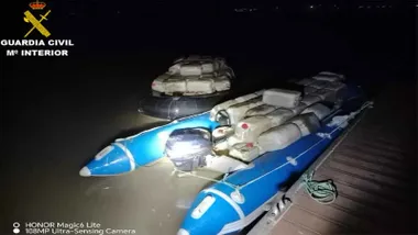 Lancha de color azul muy cargada con bidones de gasolina.