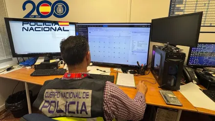 Miembro de la Policía Nacional de delitos informáticos sentado frente al ordenador controlando las redes.