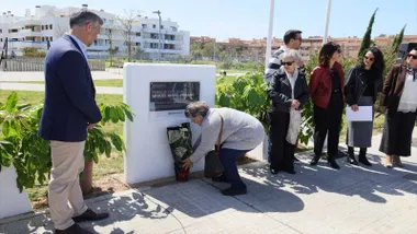 Mujer poniendo una maceta con una cala delante de la placa mientras observa el alcalde de Rota.