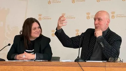 Sentados en una mesa de madera Susana Rivas y Jesús Romero que hace un gesto con la mano.