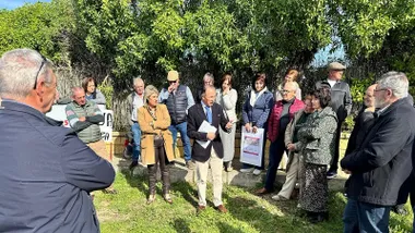 José María Román, en una zona arbolada, reunido con muchos vecinos y vecinas.