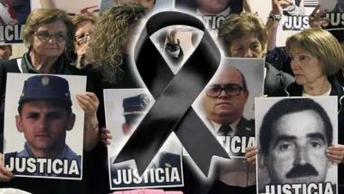 Lazo negro junto a muchas personas con carteles pidiendo justicia.