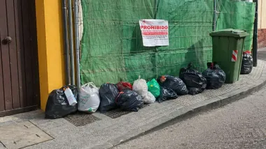 Fila de bolsas de basura alineadas en una acera de Sanlúcar.