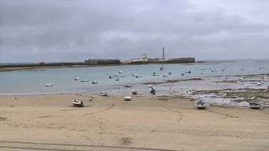 La Caleta en bajamar con el Castilllo de San Sebastián bajo un cielo nublado y gris