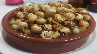 Plato de caracoles en recipiente de barro.