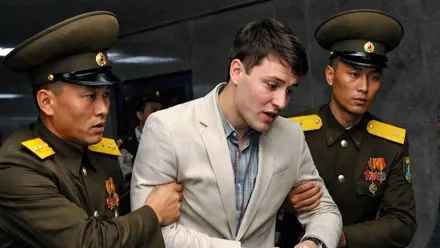 Dos soldados norcoreanos sujetan de los brazos a Otto Warmbier.