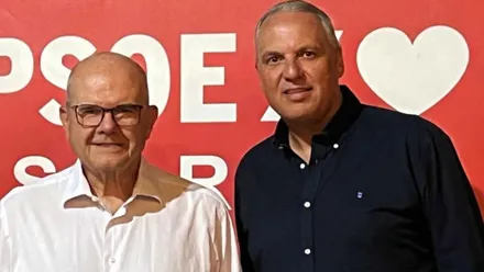 Foto delante de un cartel del PSOE en rojo de Manuel Chaves y Ruiz Boix.