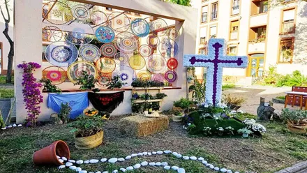 Plaza adornada con una Cruz de Mayo con flores y mantoncillos.