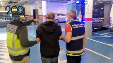 Dos policías nacionales acompañan al detenido en los garajes de comisaría.